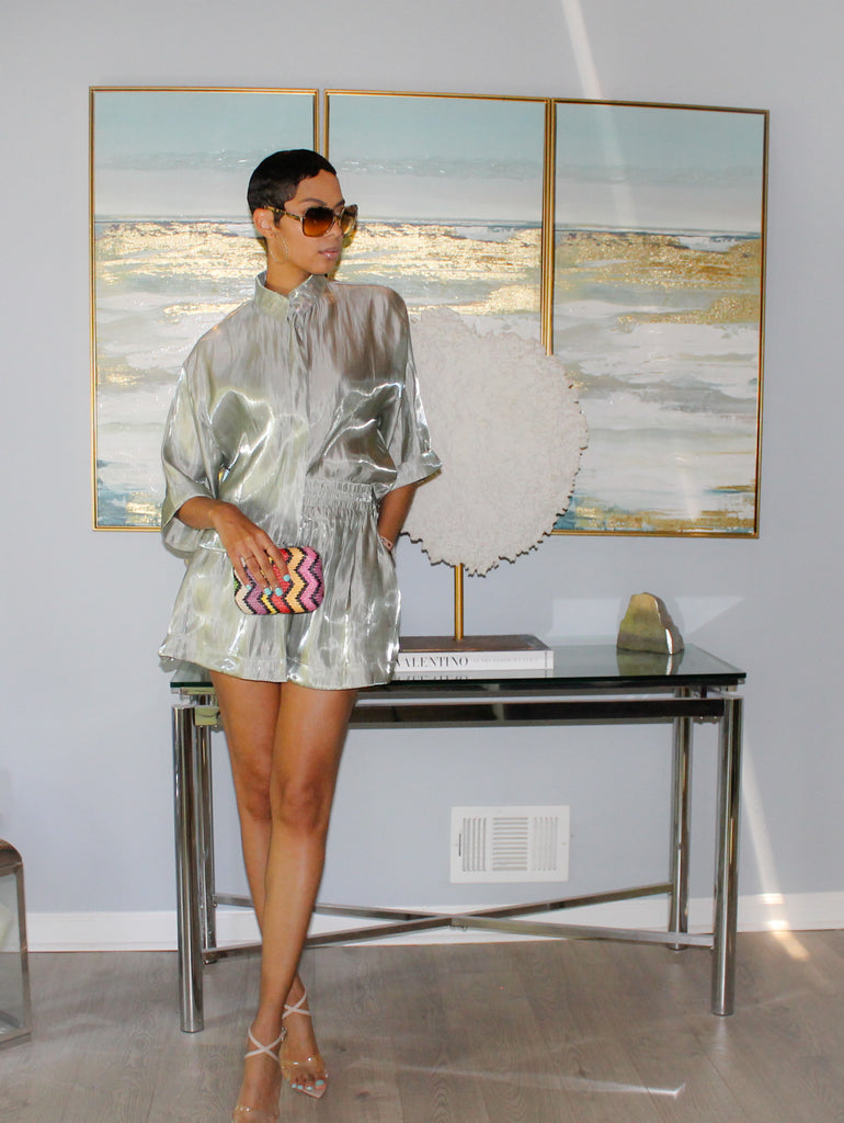 Woman in sage color iridescent metallic high-waist shorts with an elastic waistband paired with the wide short sleeves crop shirt.