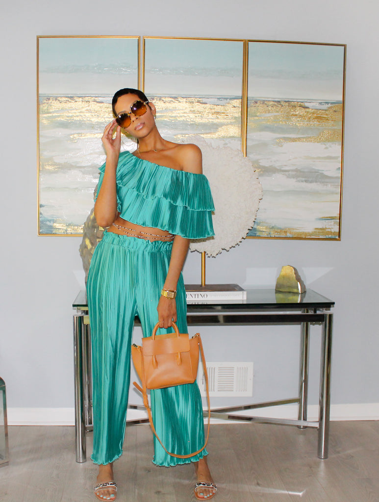 Woman in teal color off-the-shoulder crop top features delicate pleating, creating a flattering neckline that highlights your shoulders and collarbone. Paired with matching high-waist pleated pants.